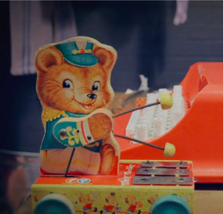 Here is a picture of a vintage toy bear struming on a xylophone