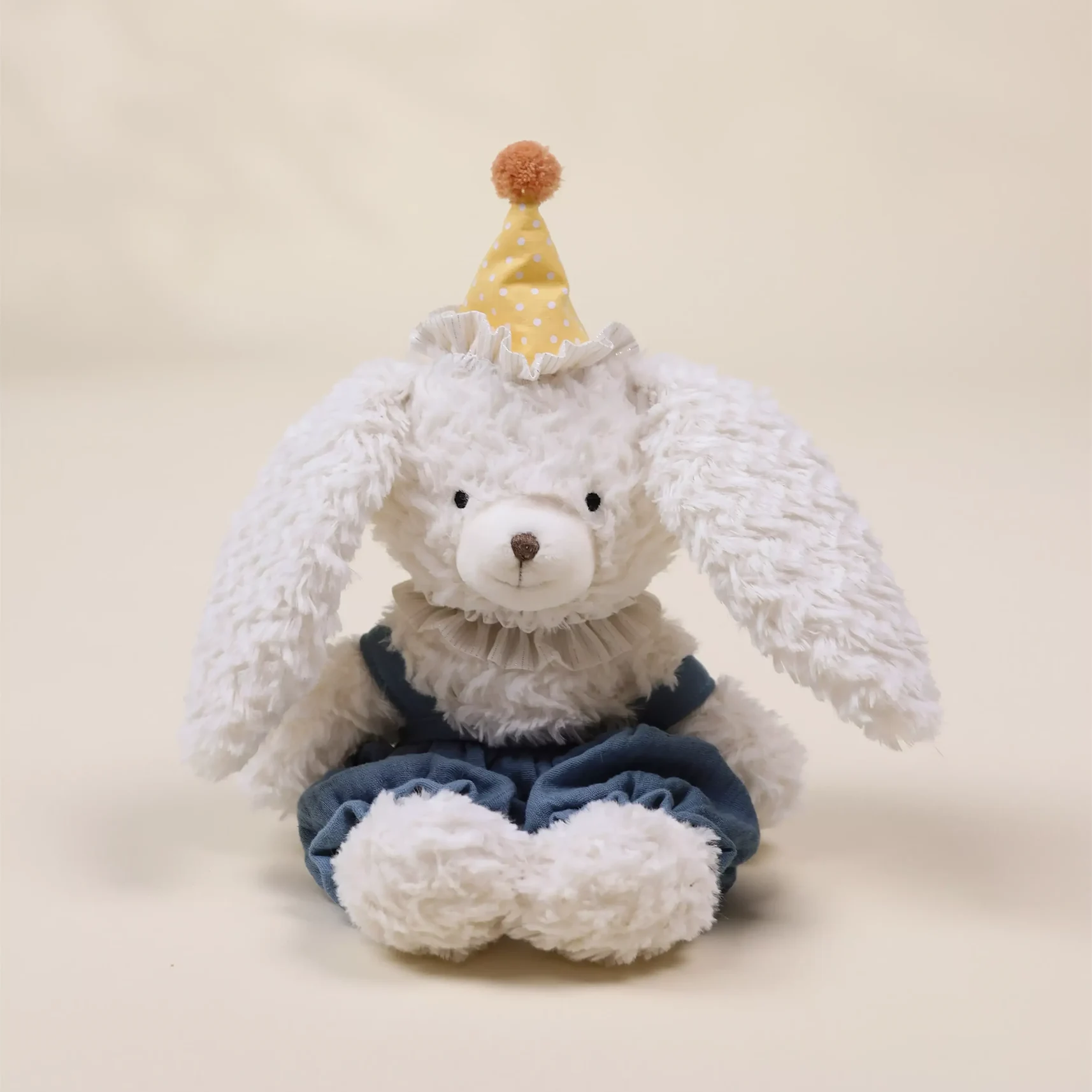 White plush bunny with a yellow hat and blue overalls on a beige background