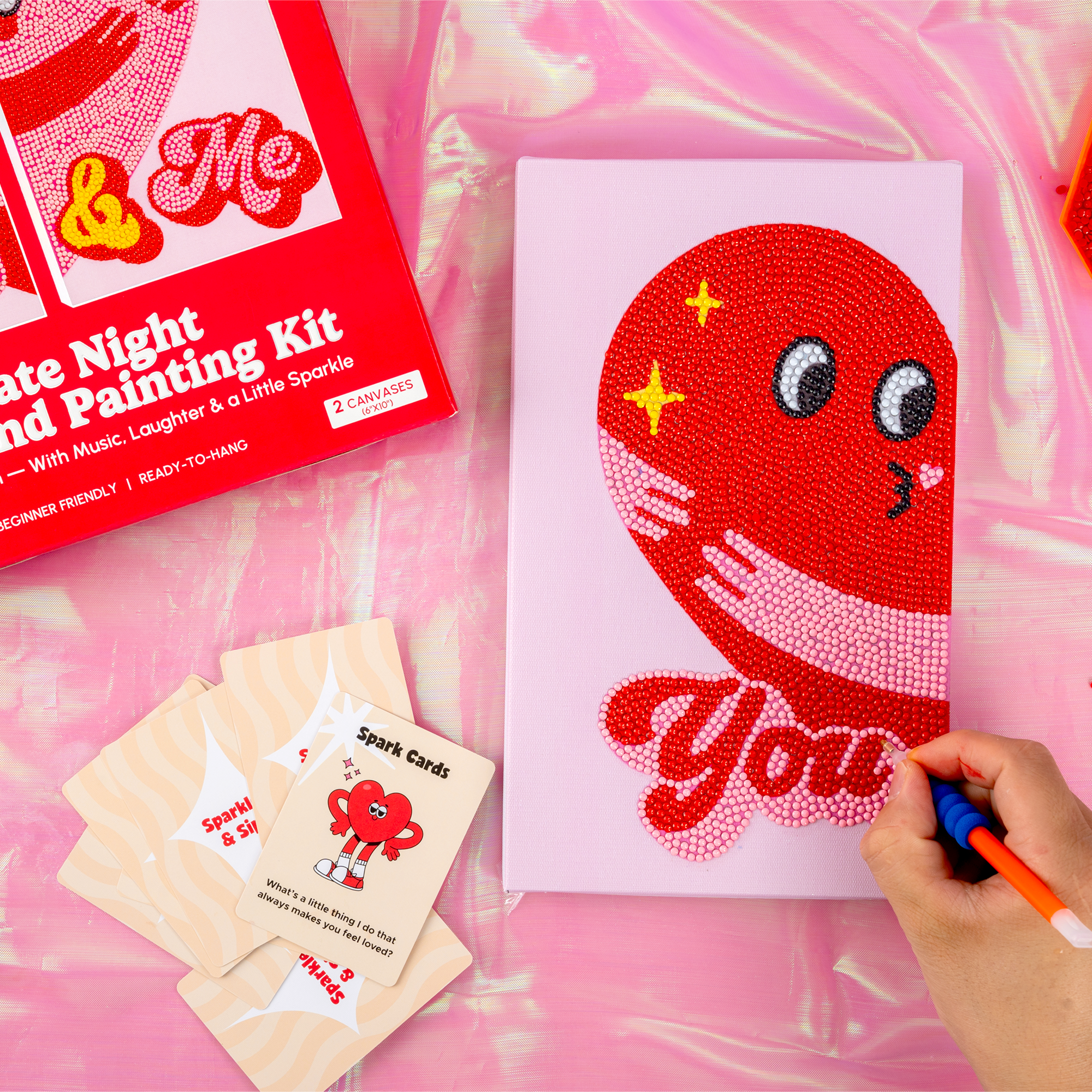 Red and white painting kit with a completed artwork on a pink surface