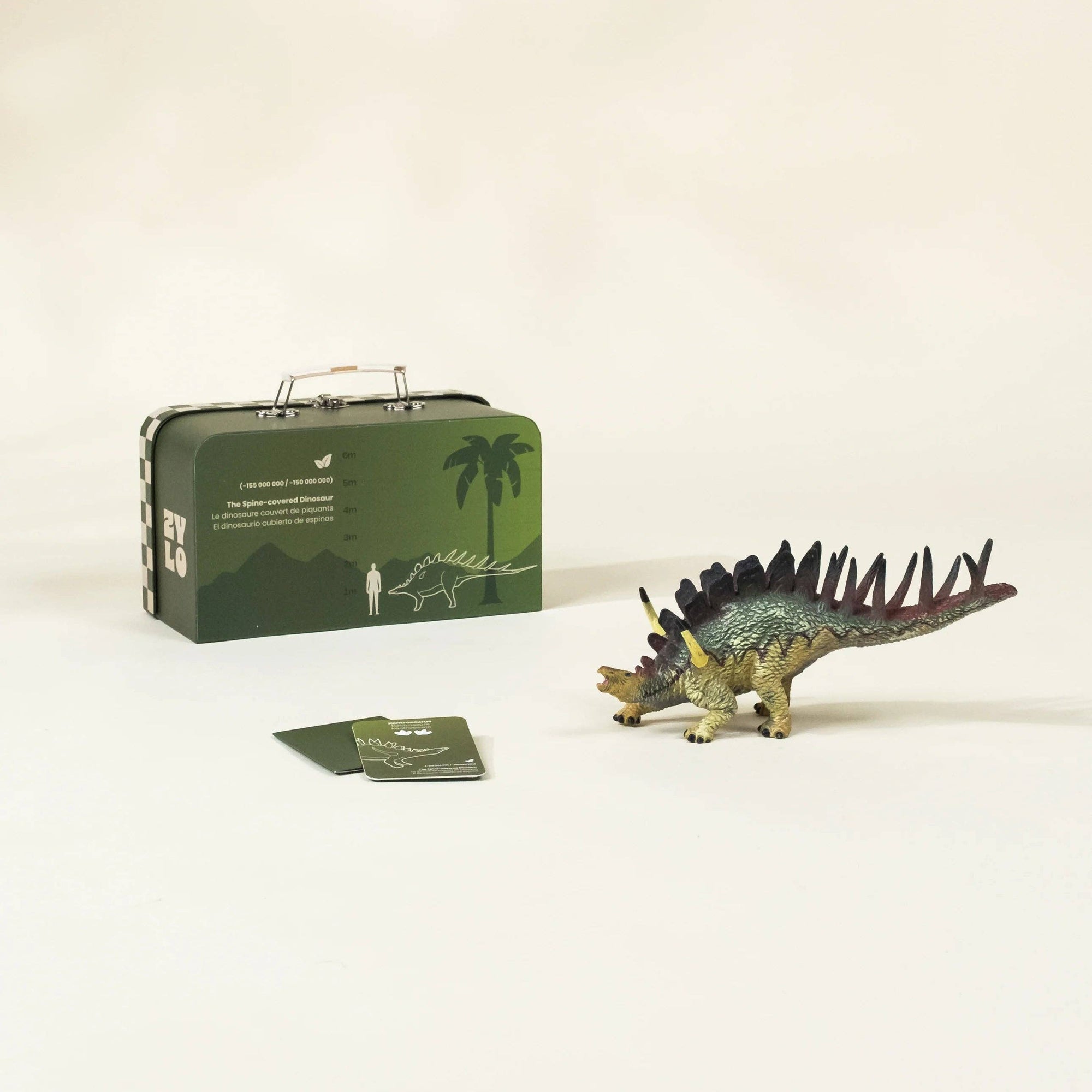 Toy dinosaur with a suitcase and cards on a beige background