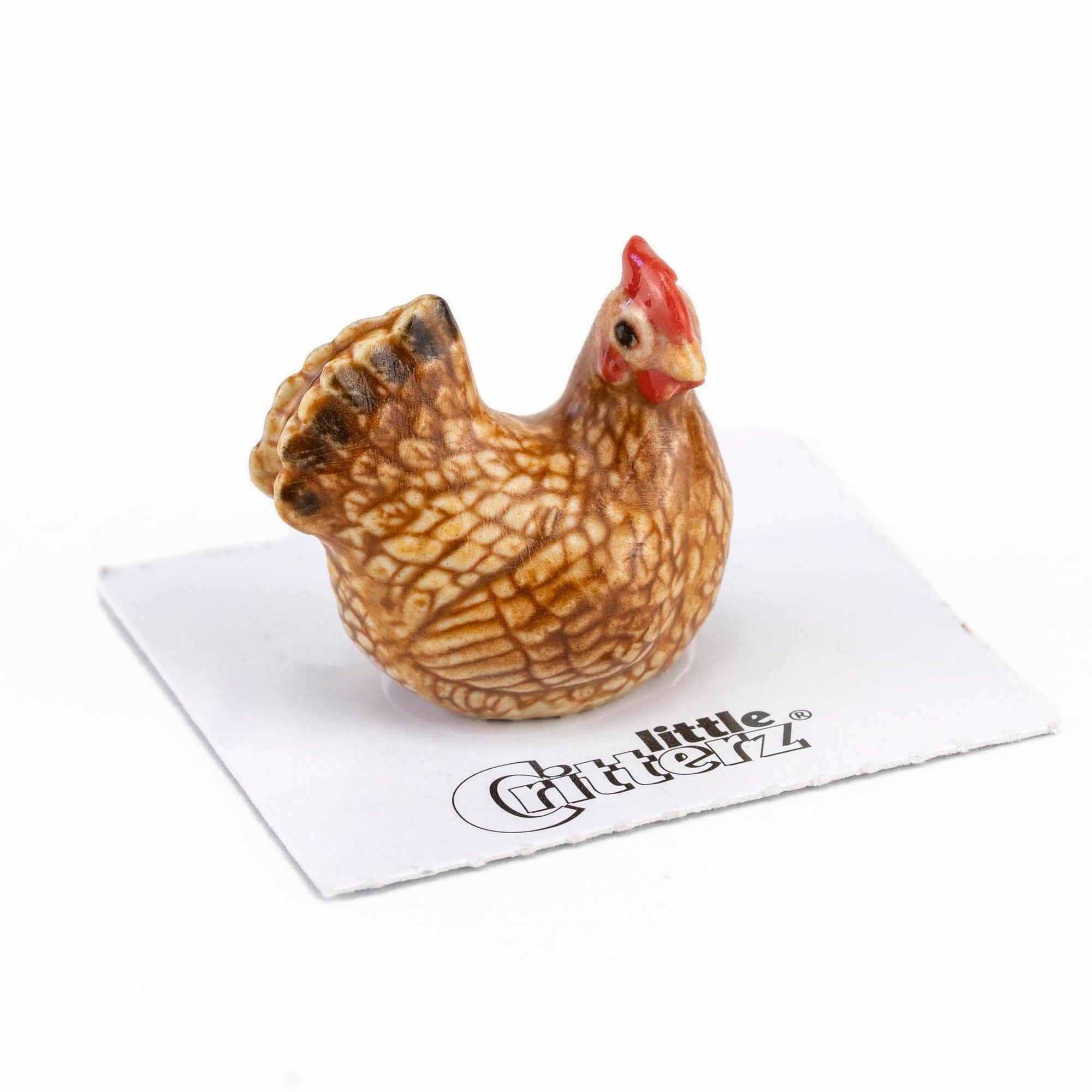 Small ceramic chicken figurine on a white napkin with 'Little Critterz' branding.