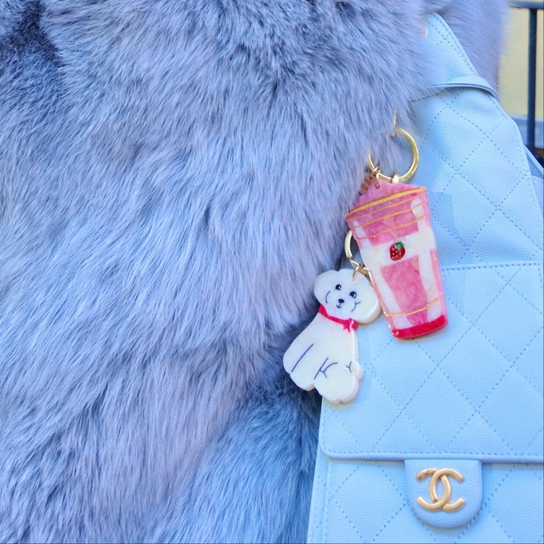 Person wearing a light blue fur coat with a Chanel handbag and keychain.