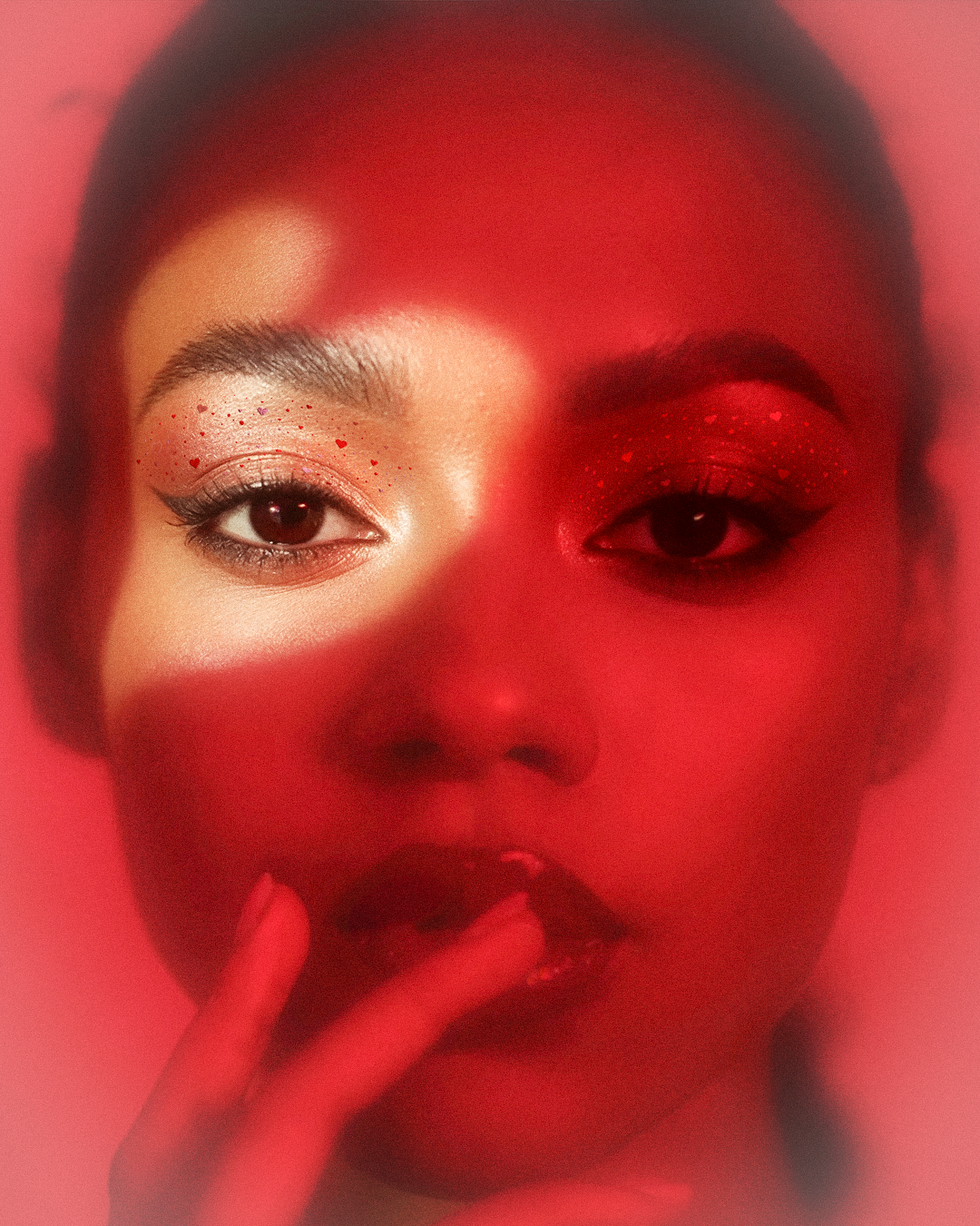 Red-toned portrait of a person with a hand near their face against a red background