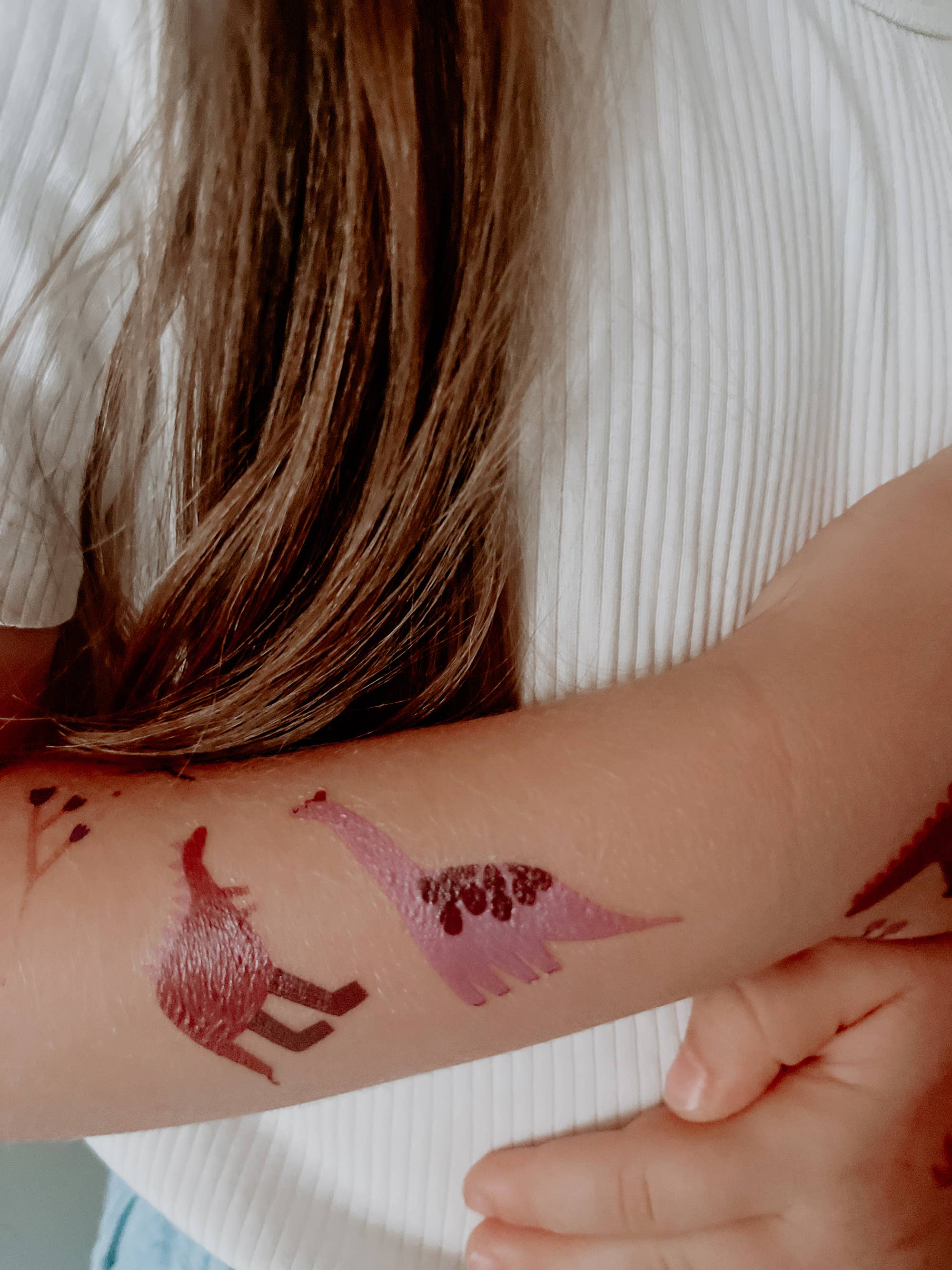 Person with temporary tattoos of a deer and a heart on their arm.