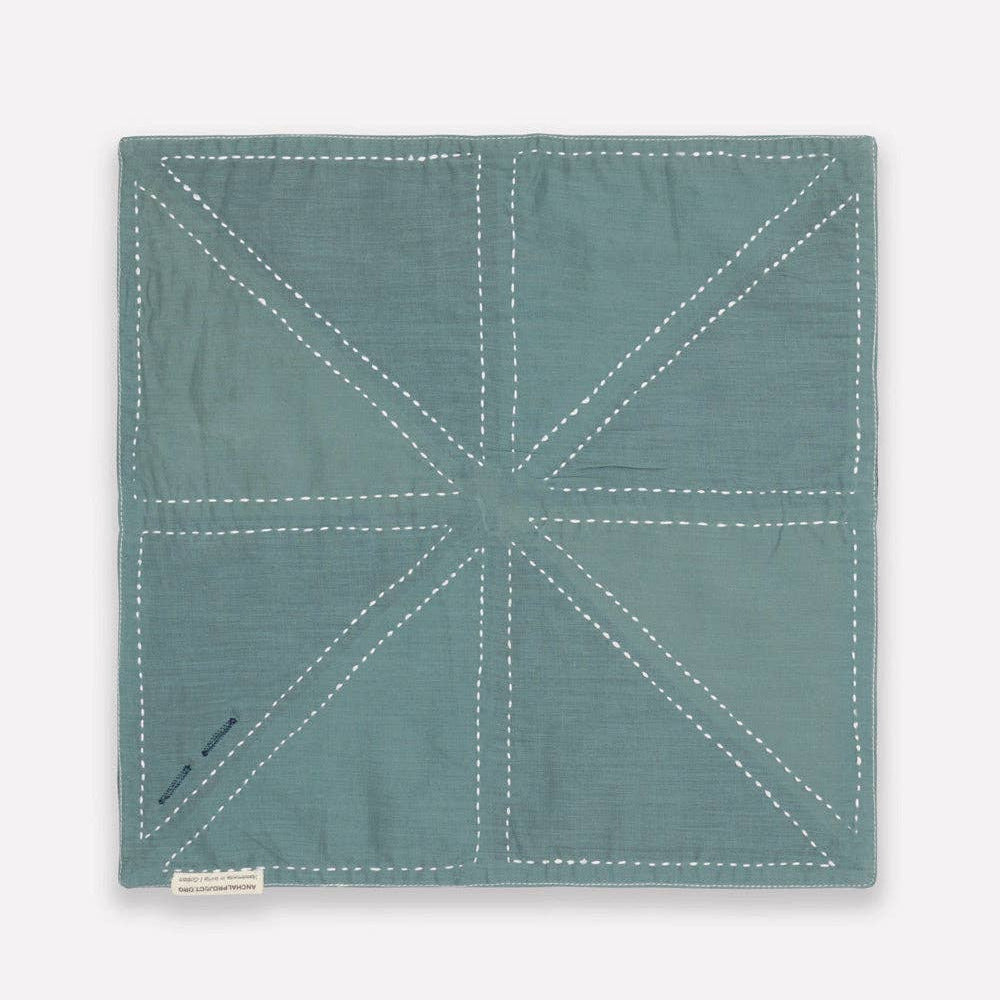 Teal fabric square with white stitching on a light gray background