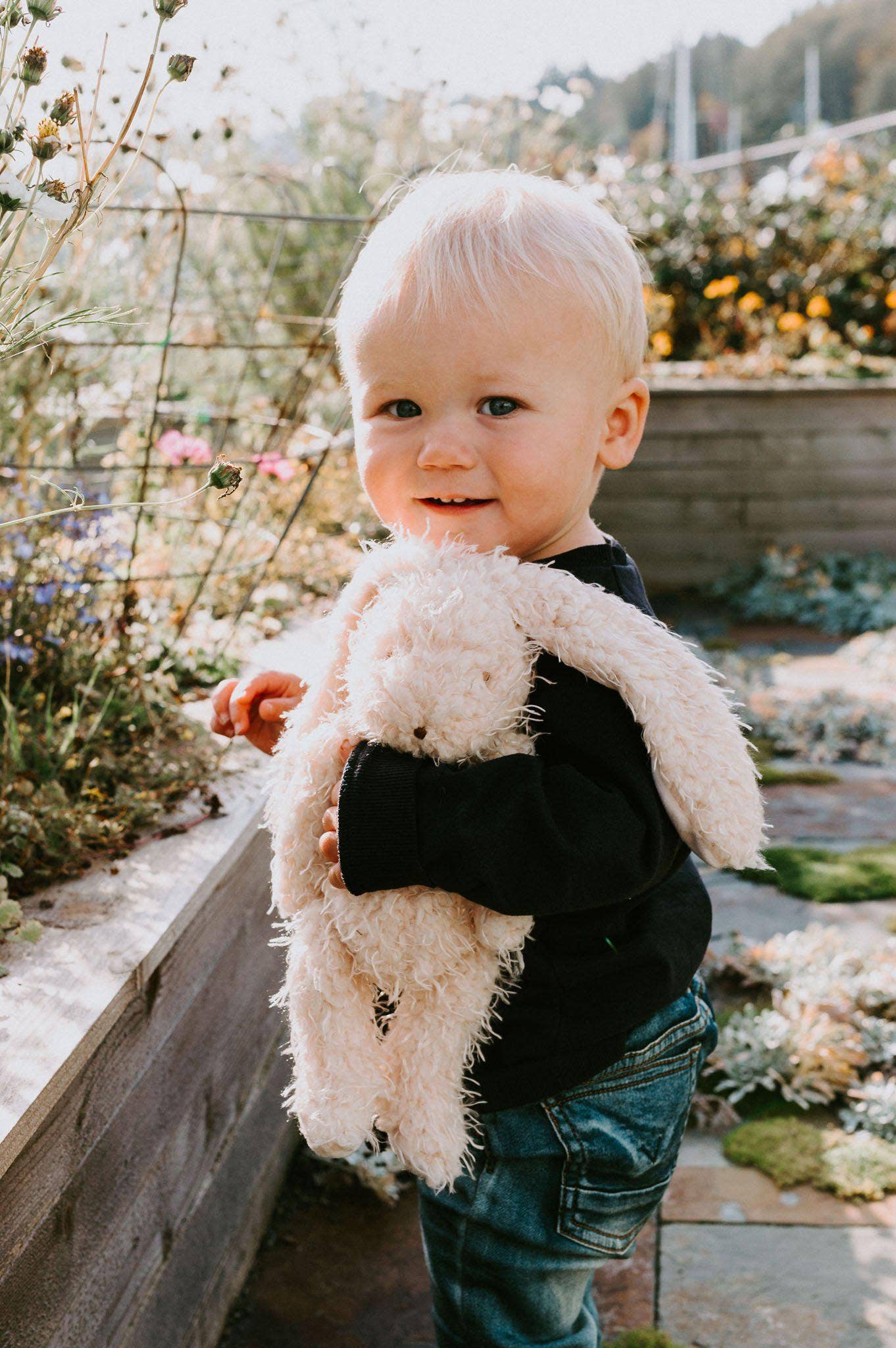 Child holding a fluffy toy in a garden setting