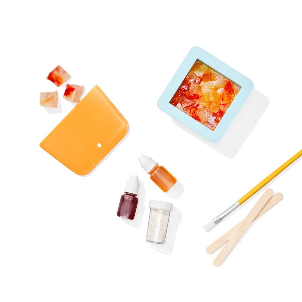 Assorted beauty products including a small square container, an orange case, and various applicators on a white background.
