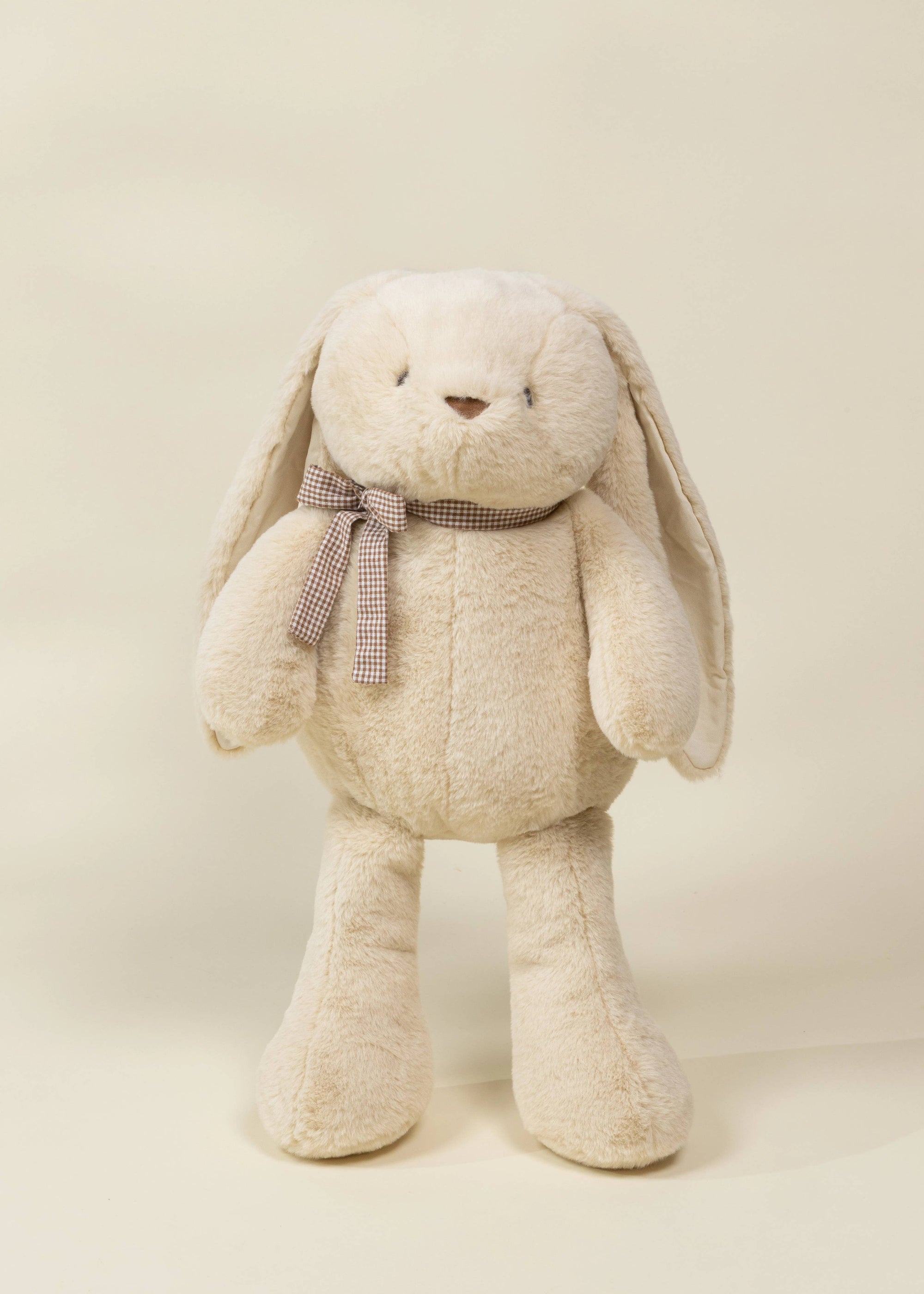 Beige stuffed bunny with a bow tie on a beige background