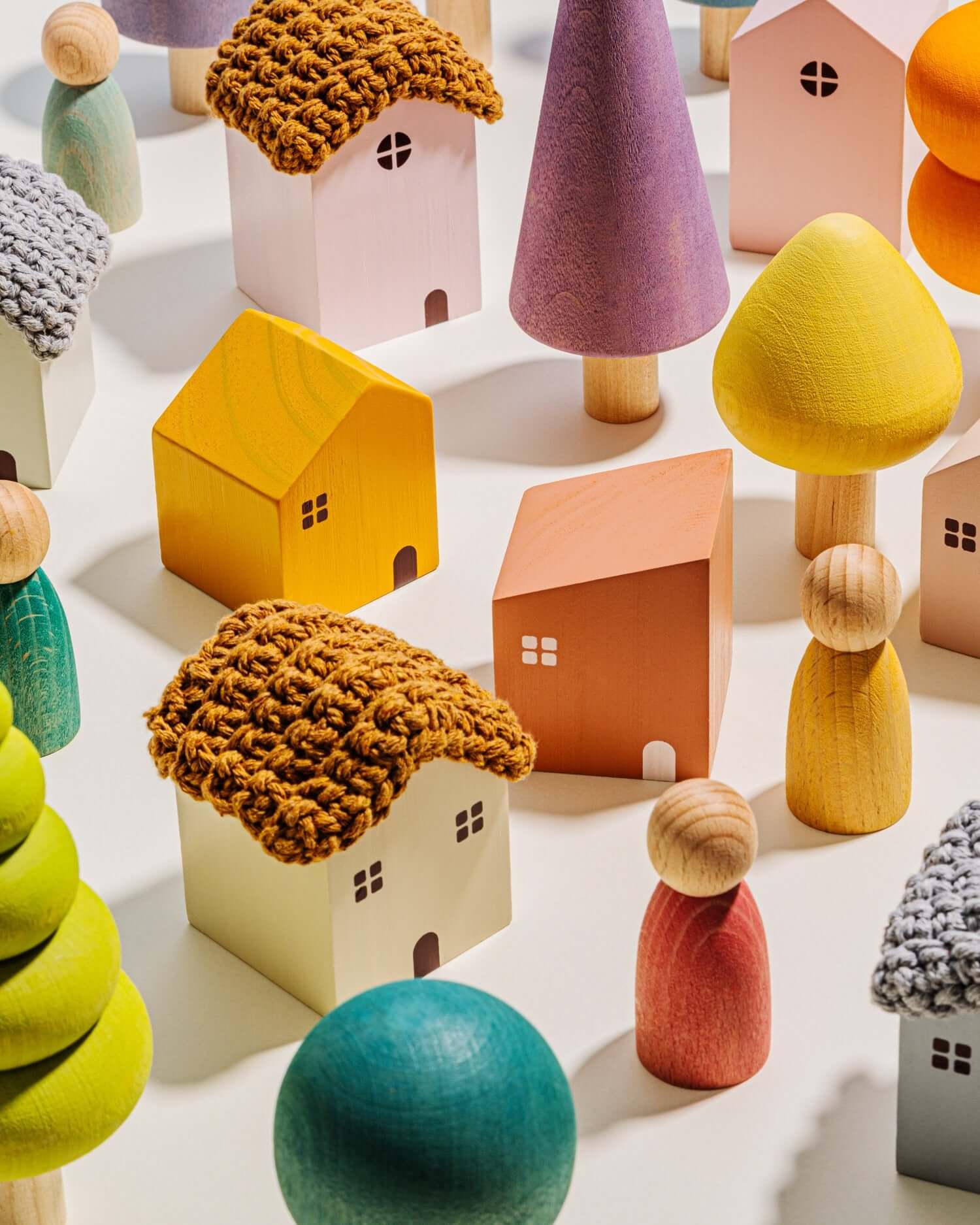 Colorful wooden toy houses and trees on a light surface