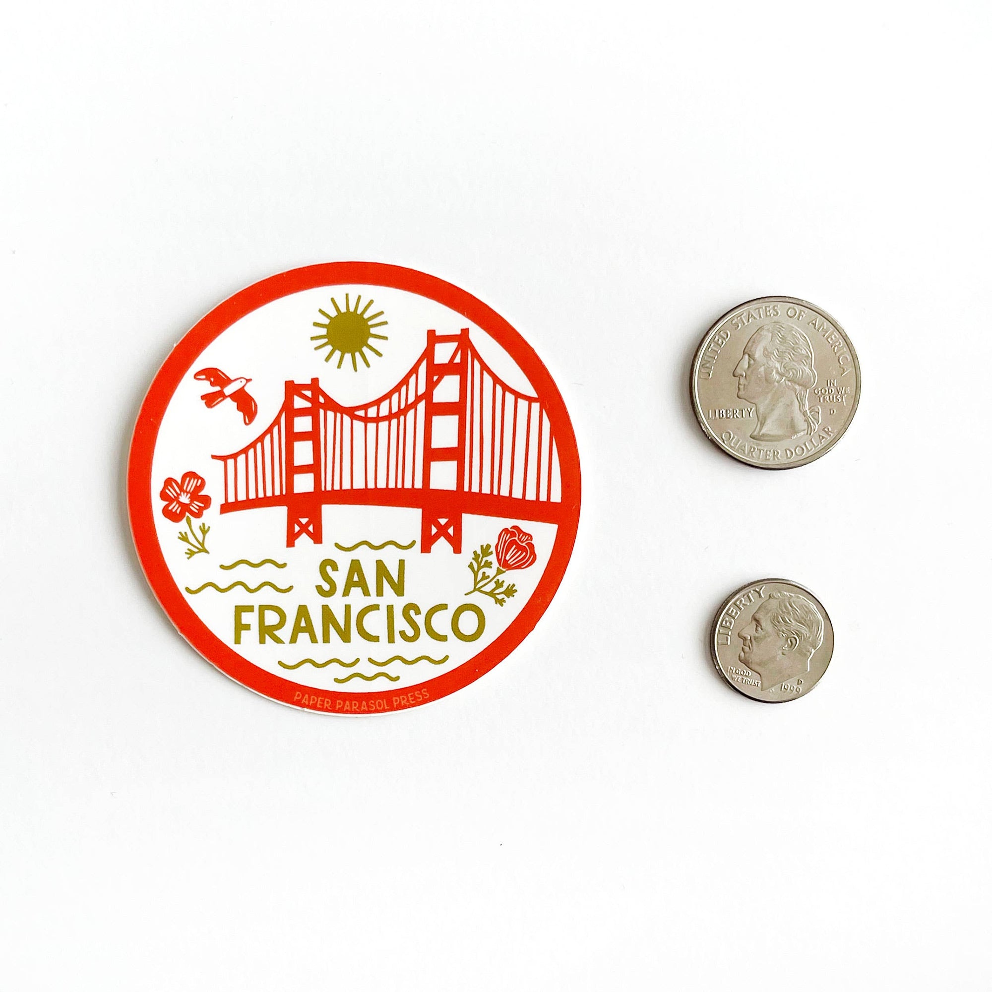 Circular sticker with Golden Gate Bridge design and 'San Francisco' text, next to two coins for size comparison on a white background.