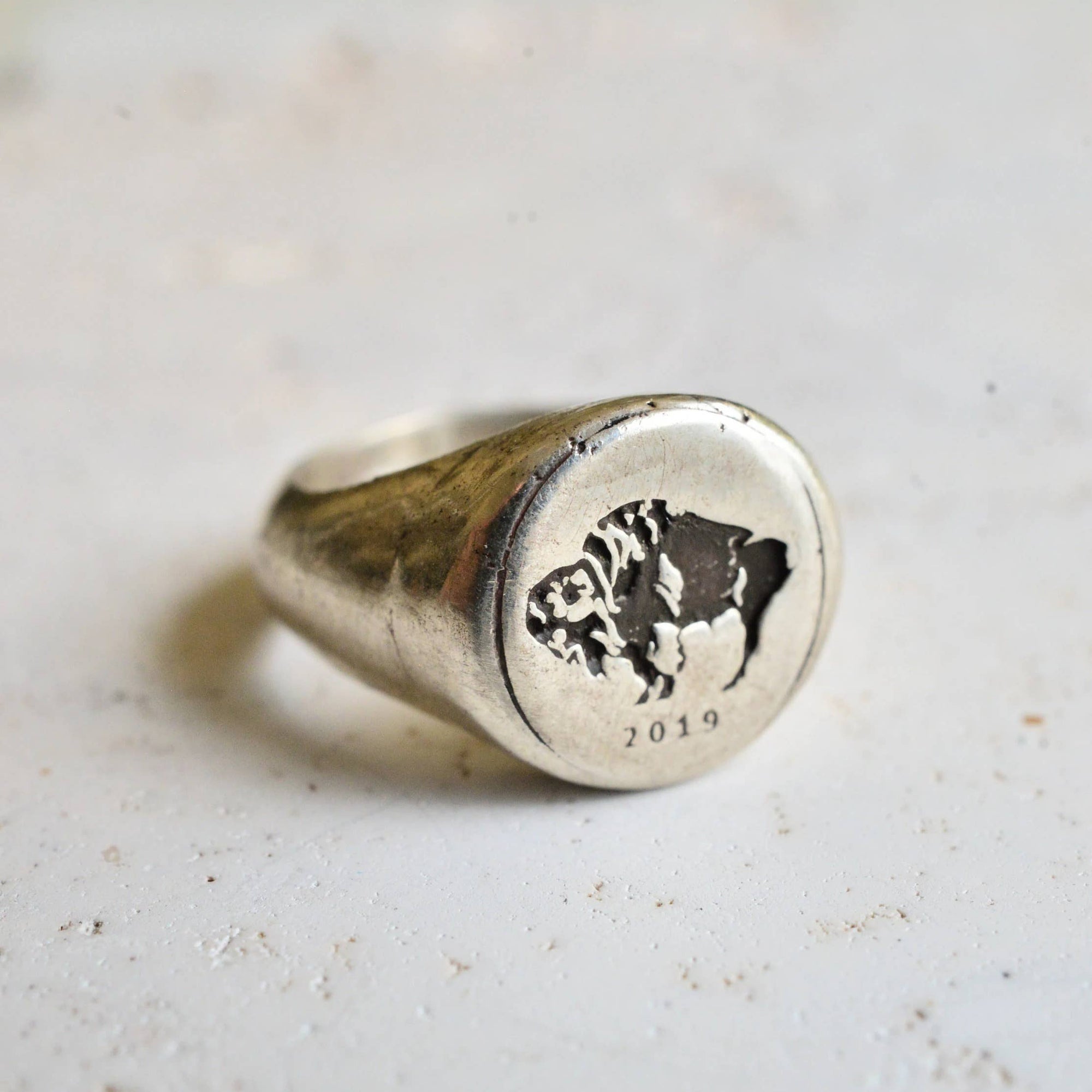 Silver ring with a black bear design on a light gray background