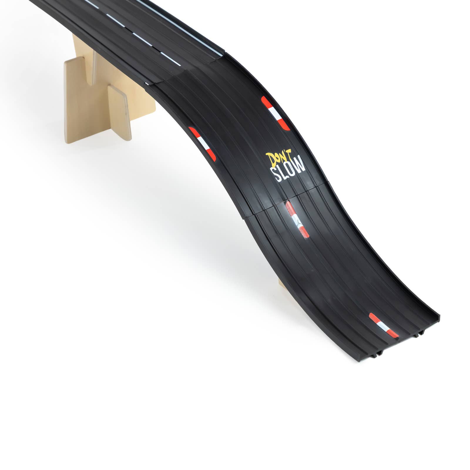 Black toy race track with a slight curve on a white background