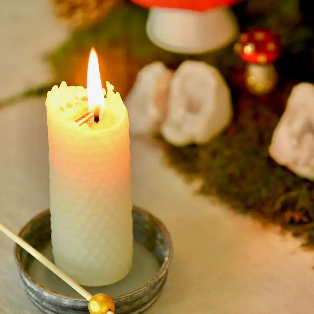 Lit candle on a small plate with a blurred background of decorative items