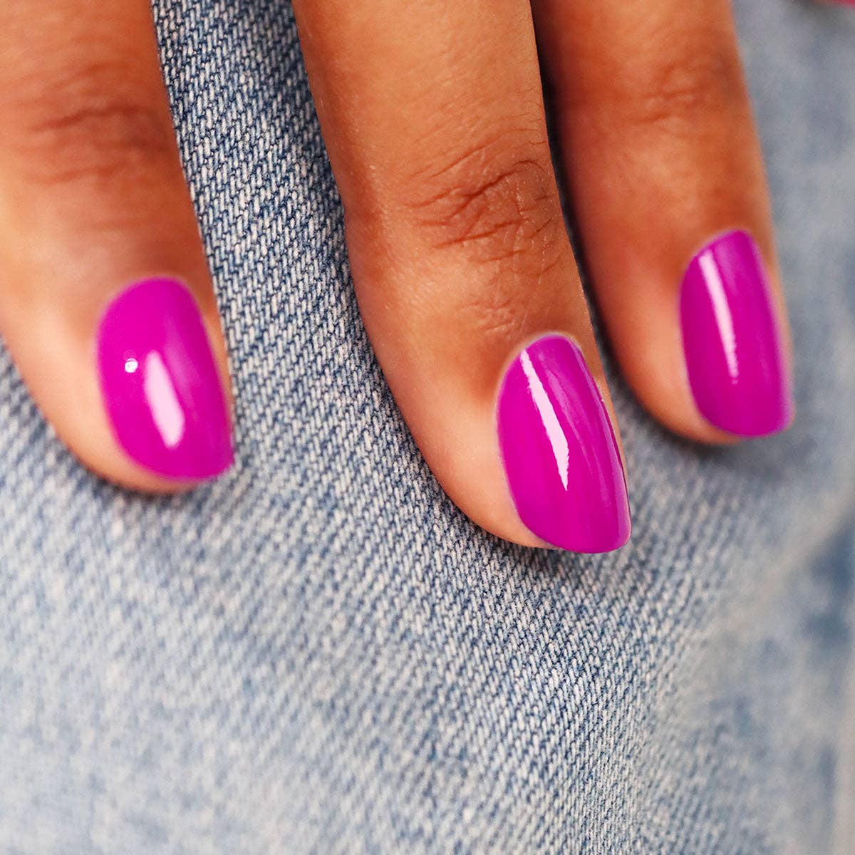 Close-up of a hand with bright pink nails on a denim background