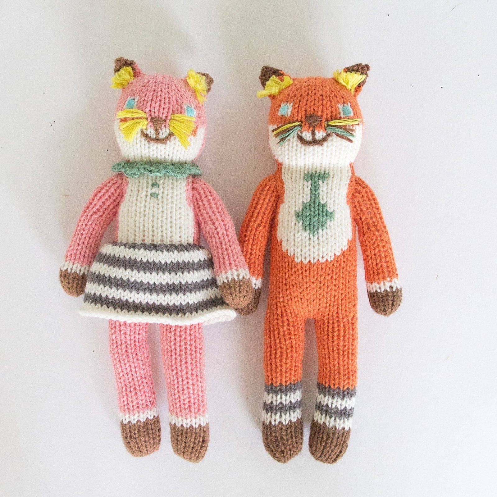 Two knitted fox toys, one in a dress and one in a suit, on a white background.