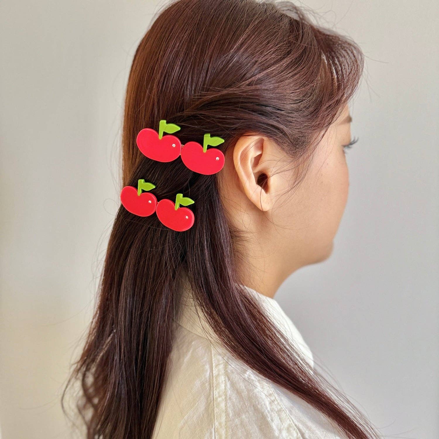 Person with apple-shaped hair clips in their hair against a neutral background