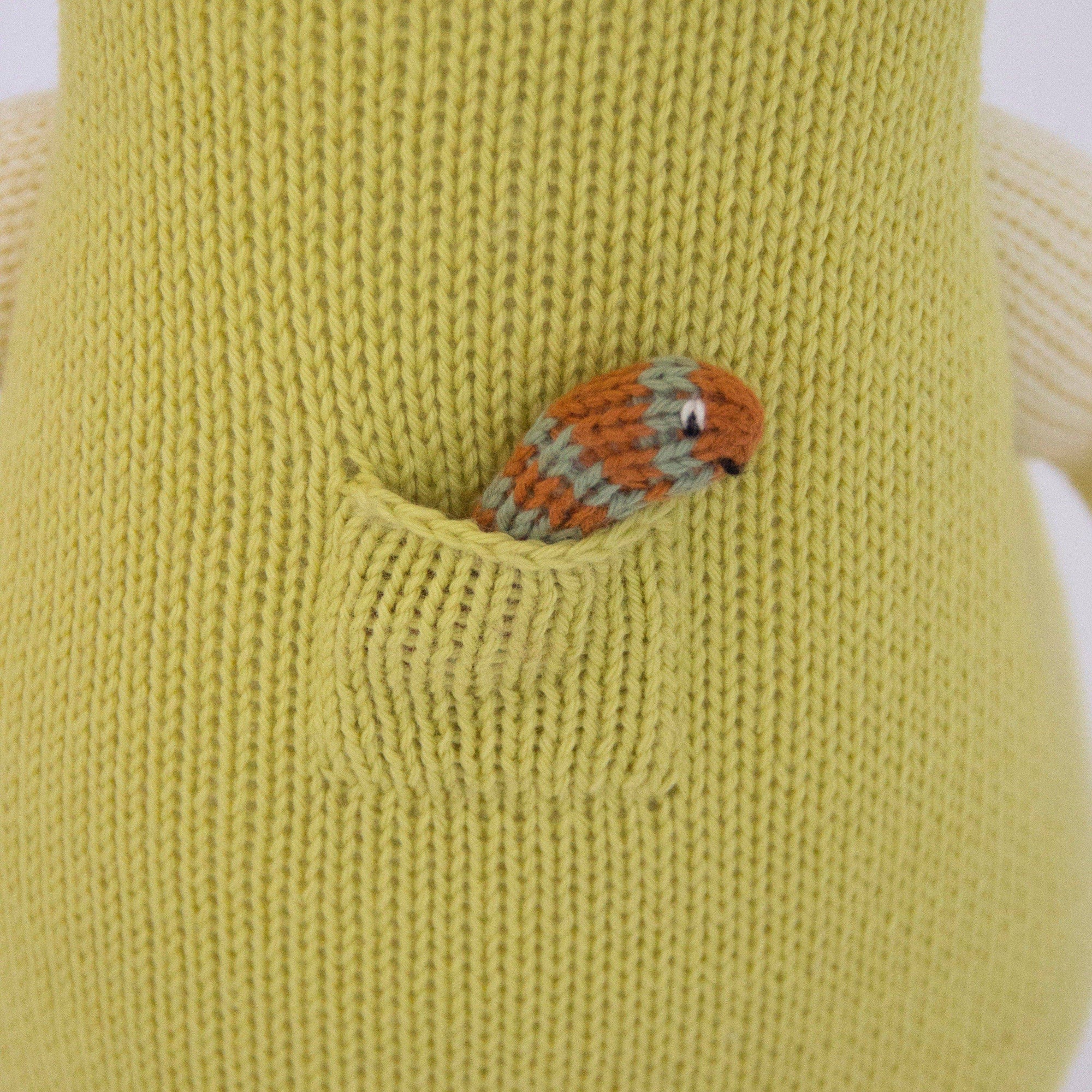 Green knitted toy with a pocket featuring a small knitted worm 