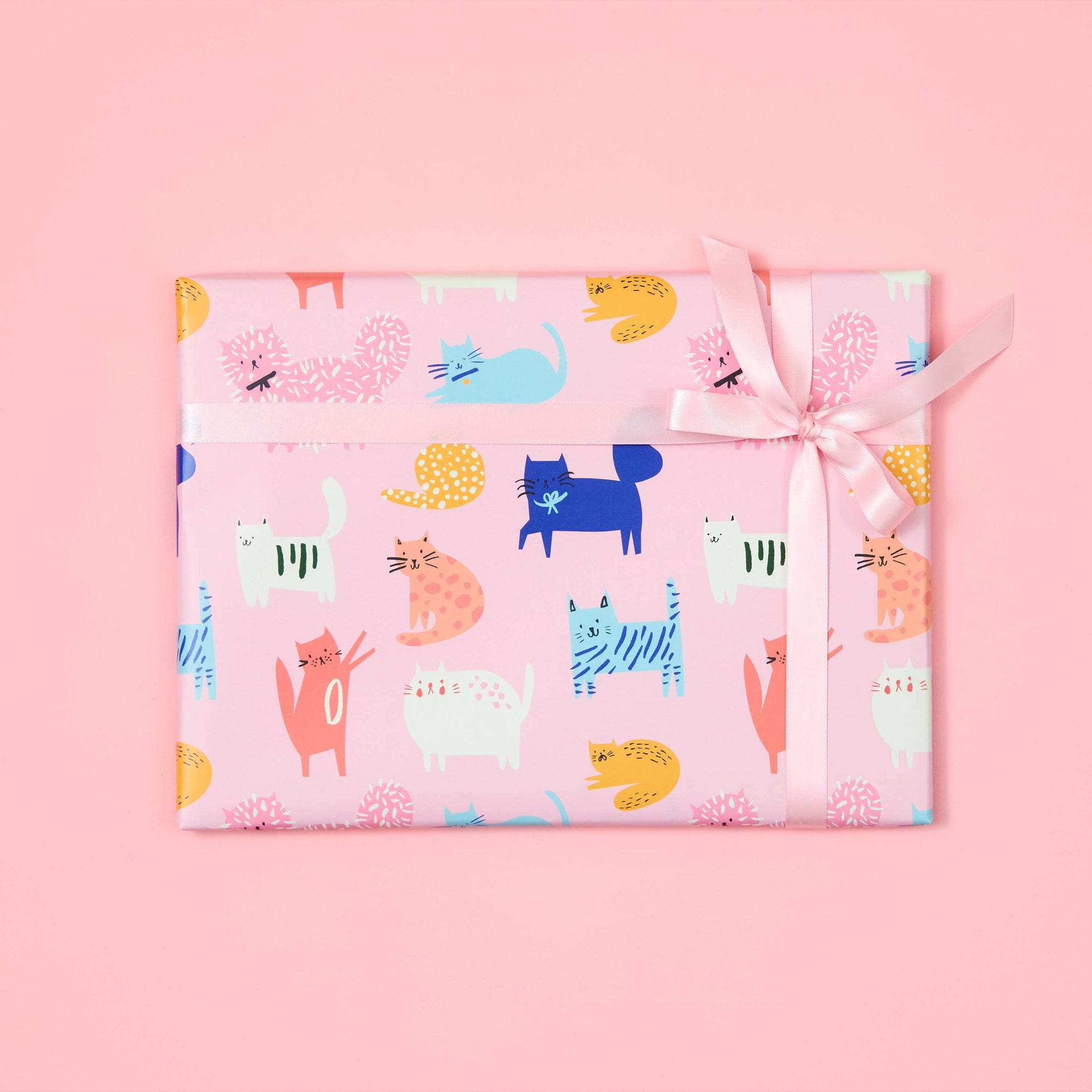 Gift wrapped in colorful animal patterned paper with a pink background
