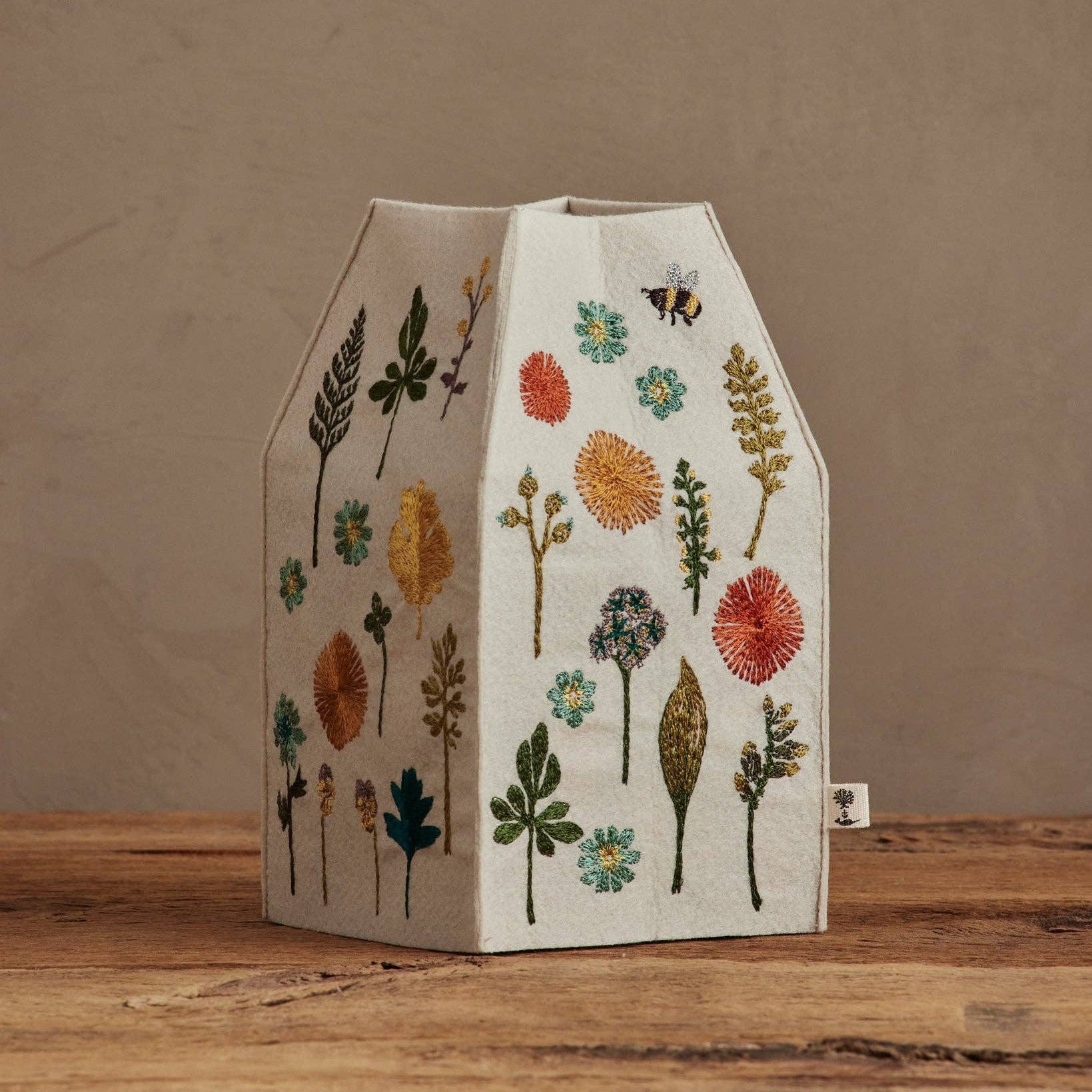 Decorative vase with floral patterns on a wooden surface and beige background