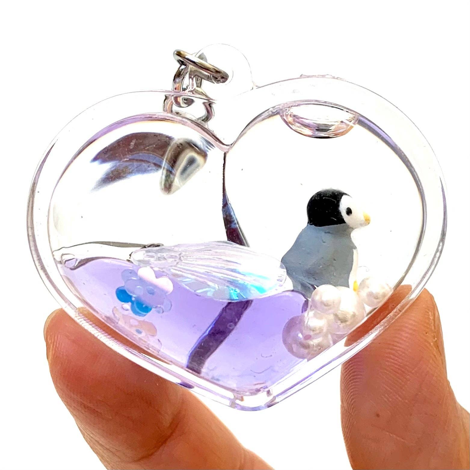 Heart-shaped pendant with a penguin inside on a white background