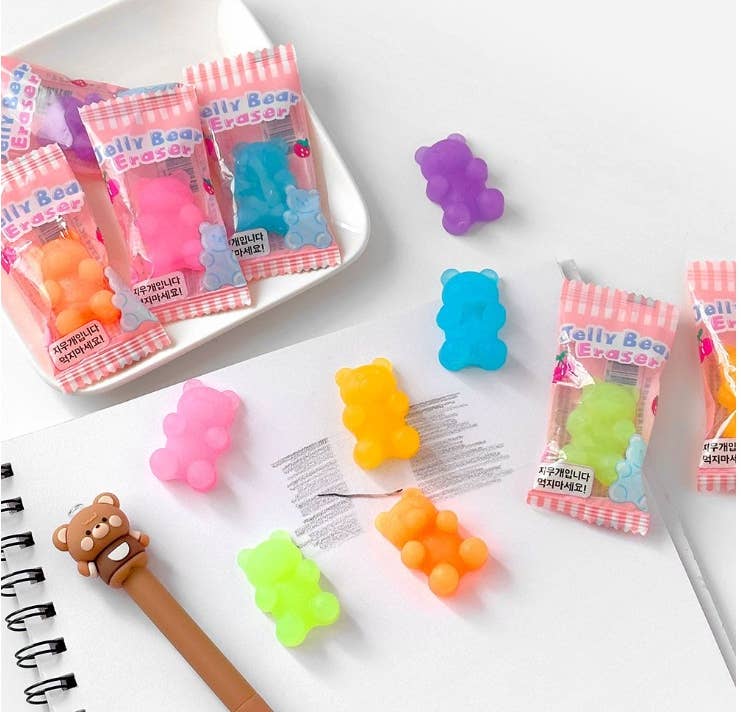 Colorful jelly bean-shaped erasers with packaging on a white surface.