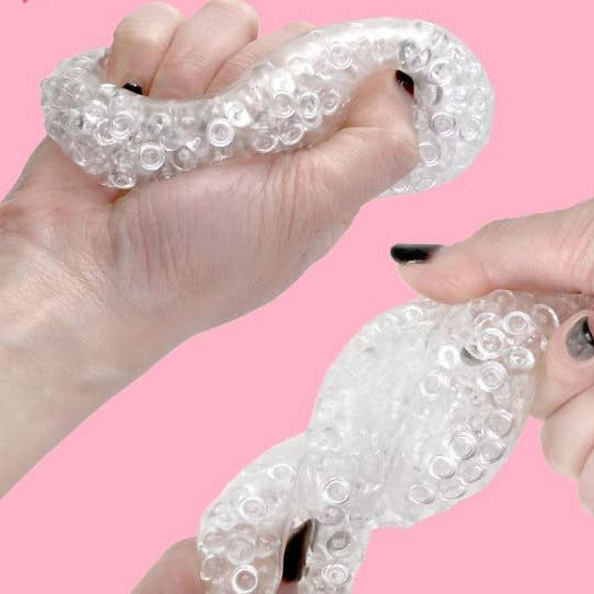 Clear silicone gloves with bubble texture held by hands against a pink background