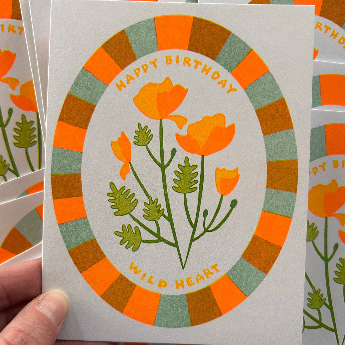 Hand holding a birthday card with floral design and 'Happy Birthday, Wild Heart' text.