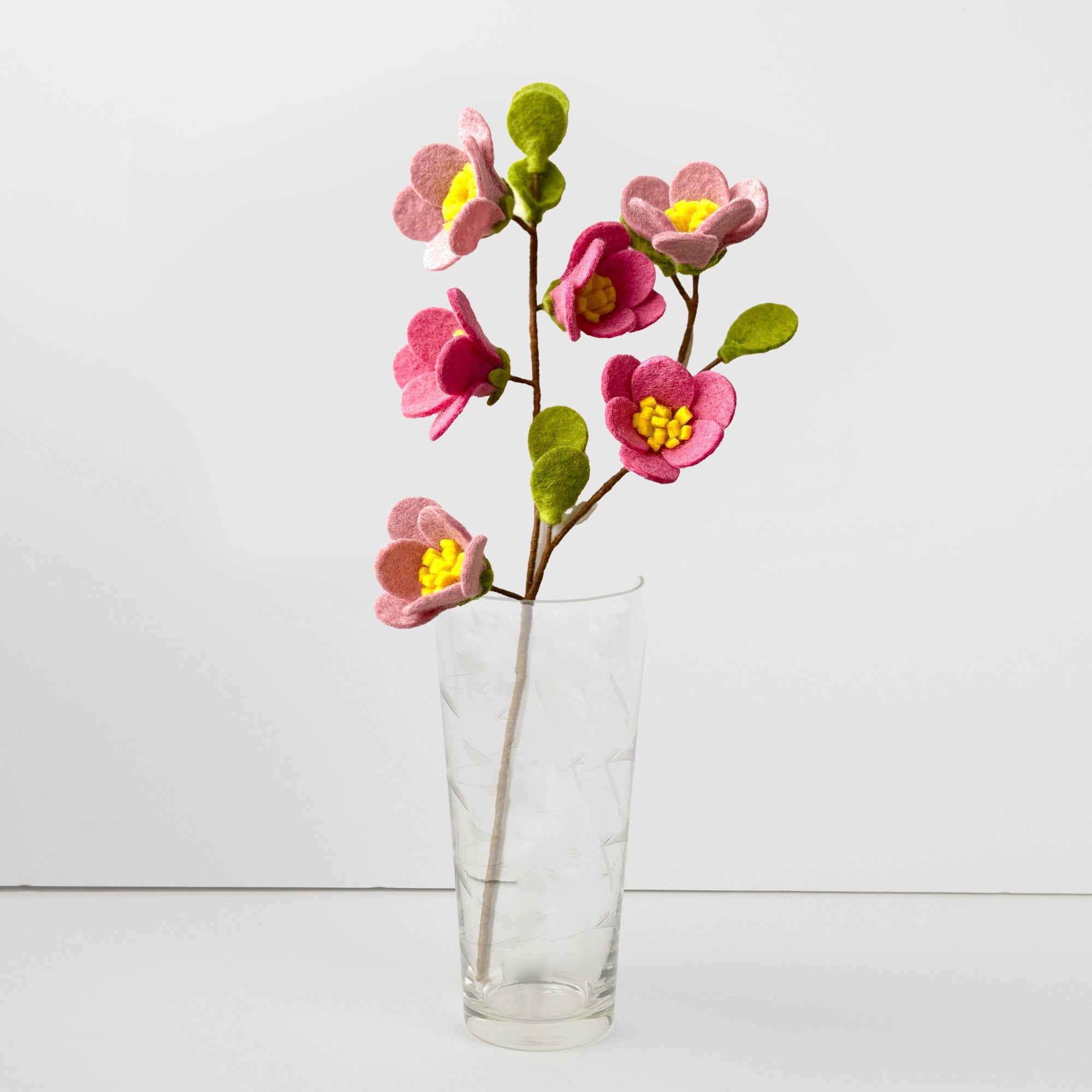 Clear glass vase with pink artificial flowers on a white background