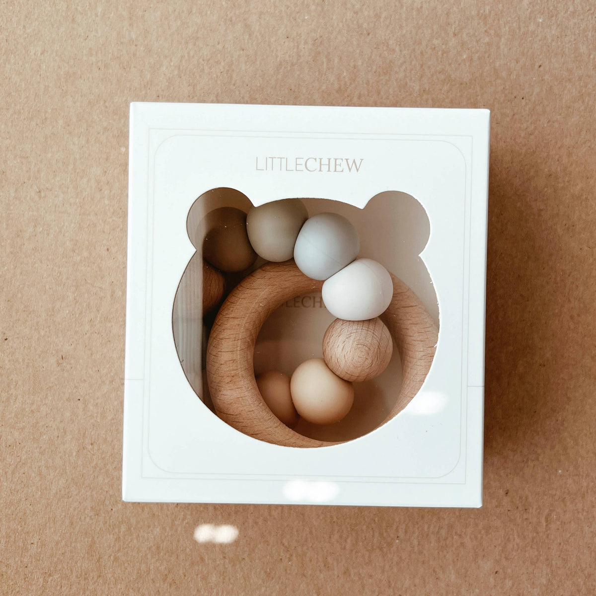 Wooden baby teething rings in a white box on a brown background