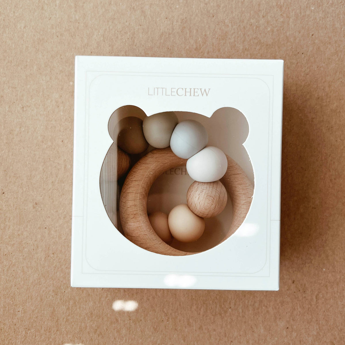 Wooden baby teething rings in a white box on a brown background