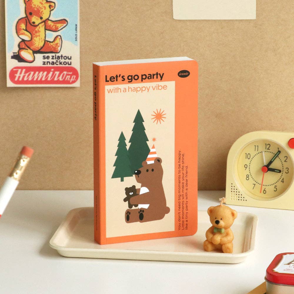 Book titled 'Let's go party with a happy vibe' on a tray with decorative items in the background