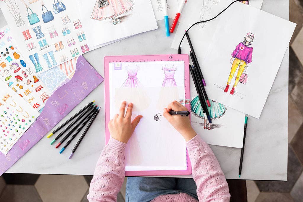 Child drawing on a tablet with fashion illustrations around