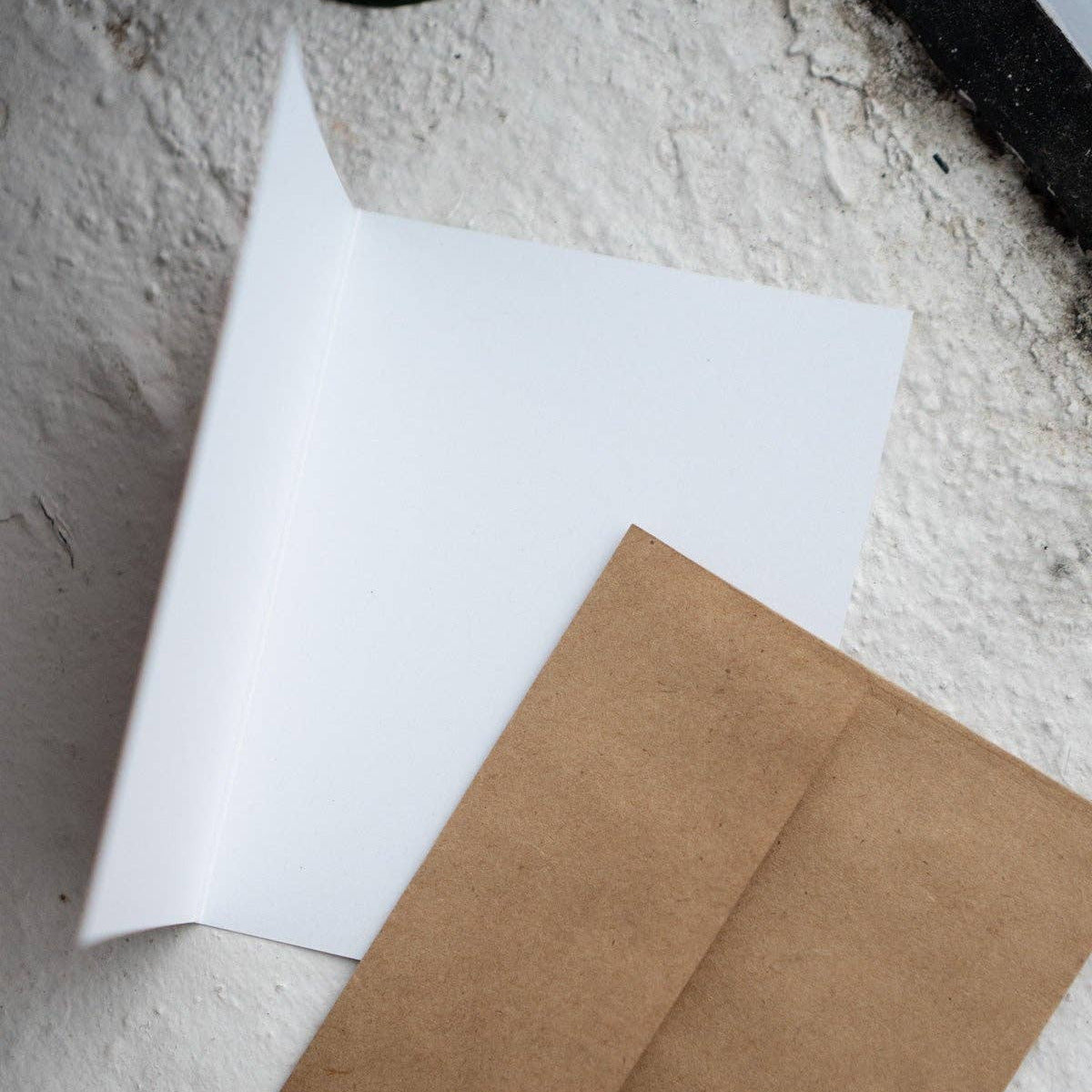 White sheet of paper and brown envelope on a textured surface