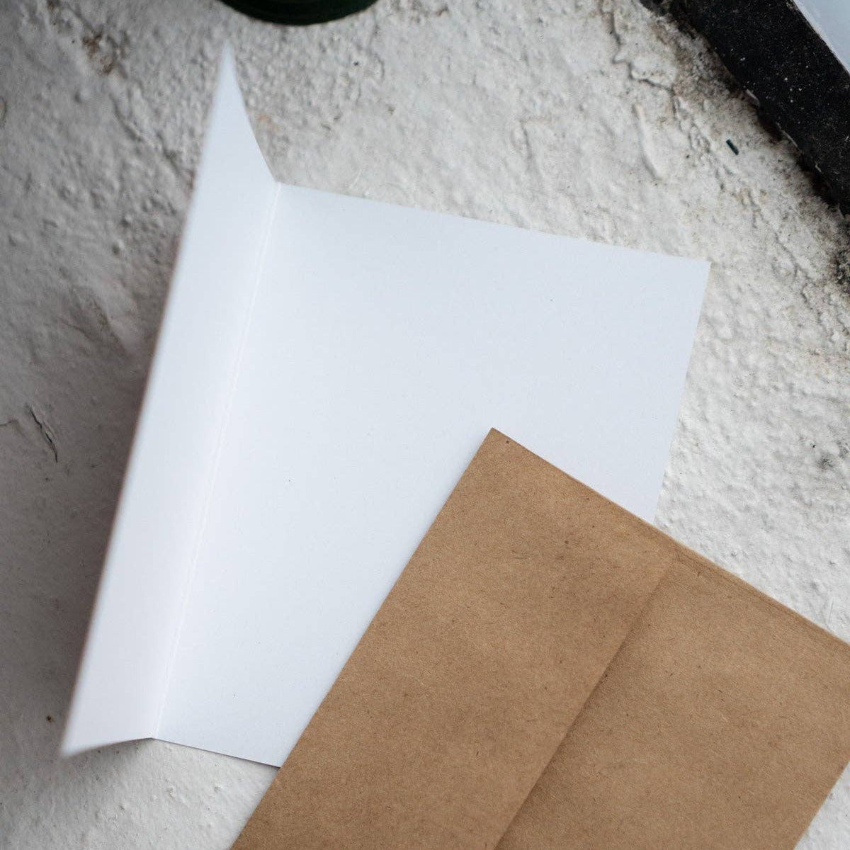 White sheet of paper and brown envelope on a textured surface