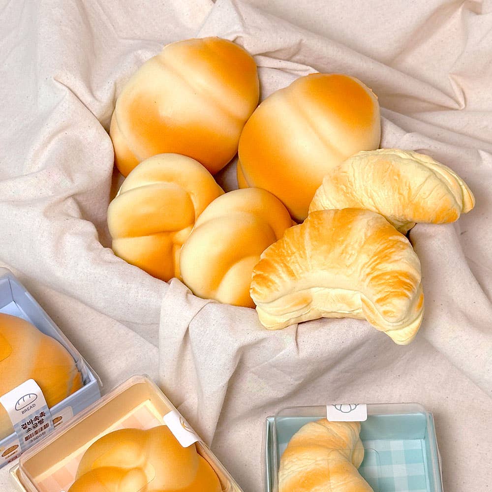 Assorted bread rolls including croissants on a light fabric background