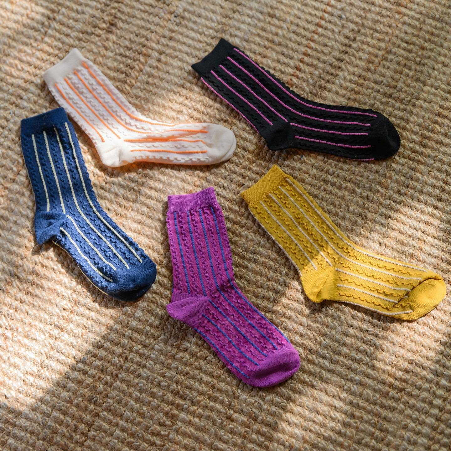 Five pairs of colorful striped socks on a textured surface