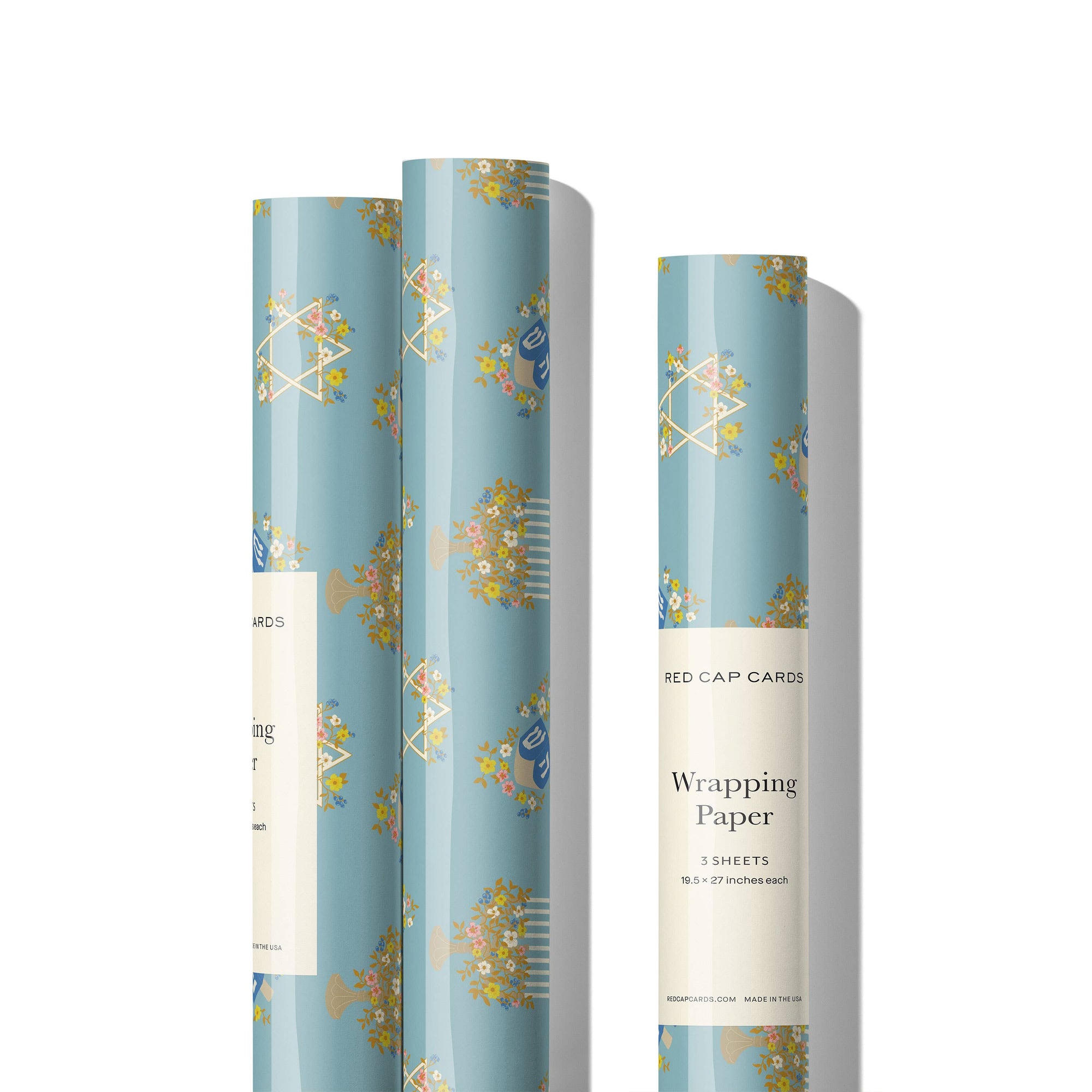 Three rolls of wrapping paper with floral designs on a white background