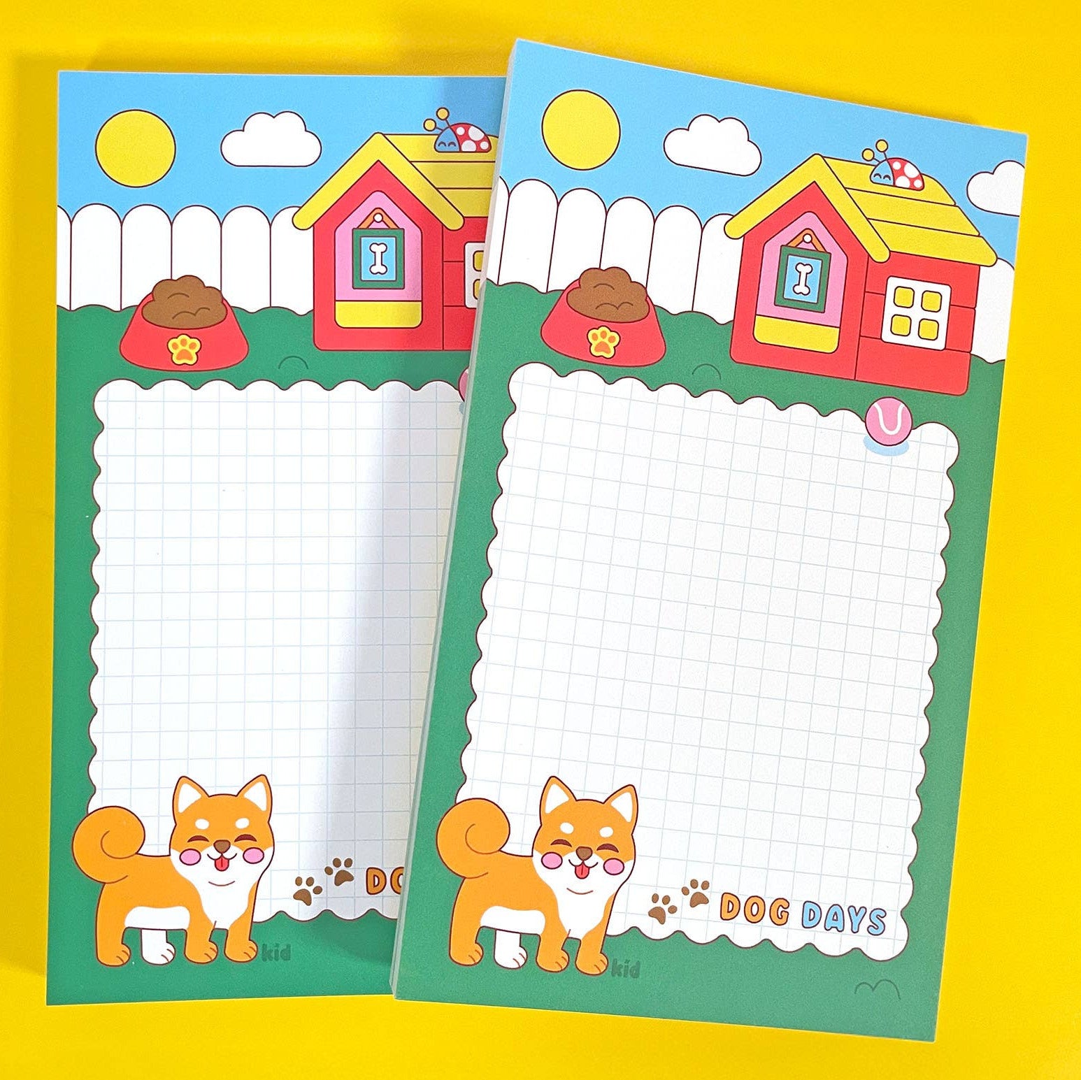Two colorful notepads with cartoon foxes and dog houses on a yellow background