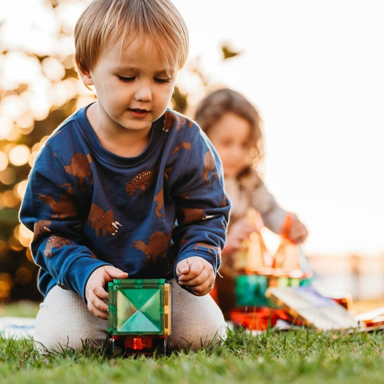 Child playing with a toy train set outdoors on a grassy area