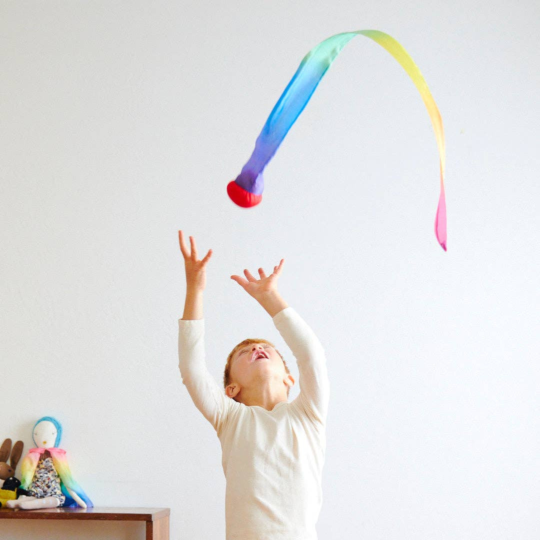 Child playing with a colorful toy against a white wall