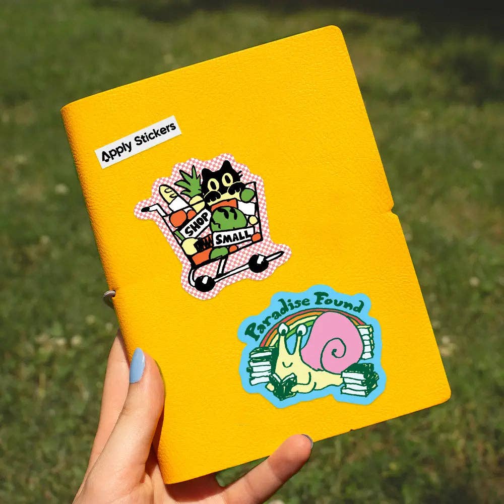 Yellow notebook with stickers on a grassy background