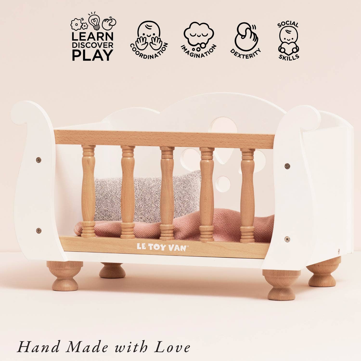 Wooden crib with white mattress and 'Le Toy Van' branding on a light pink background.