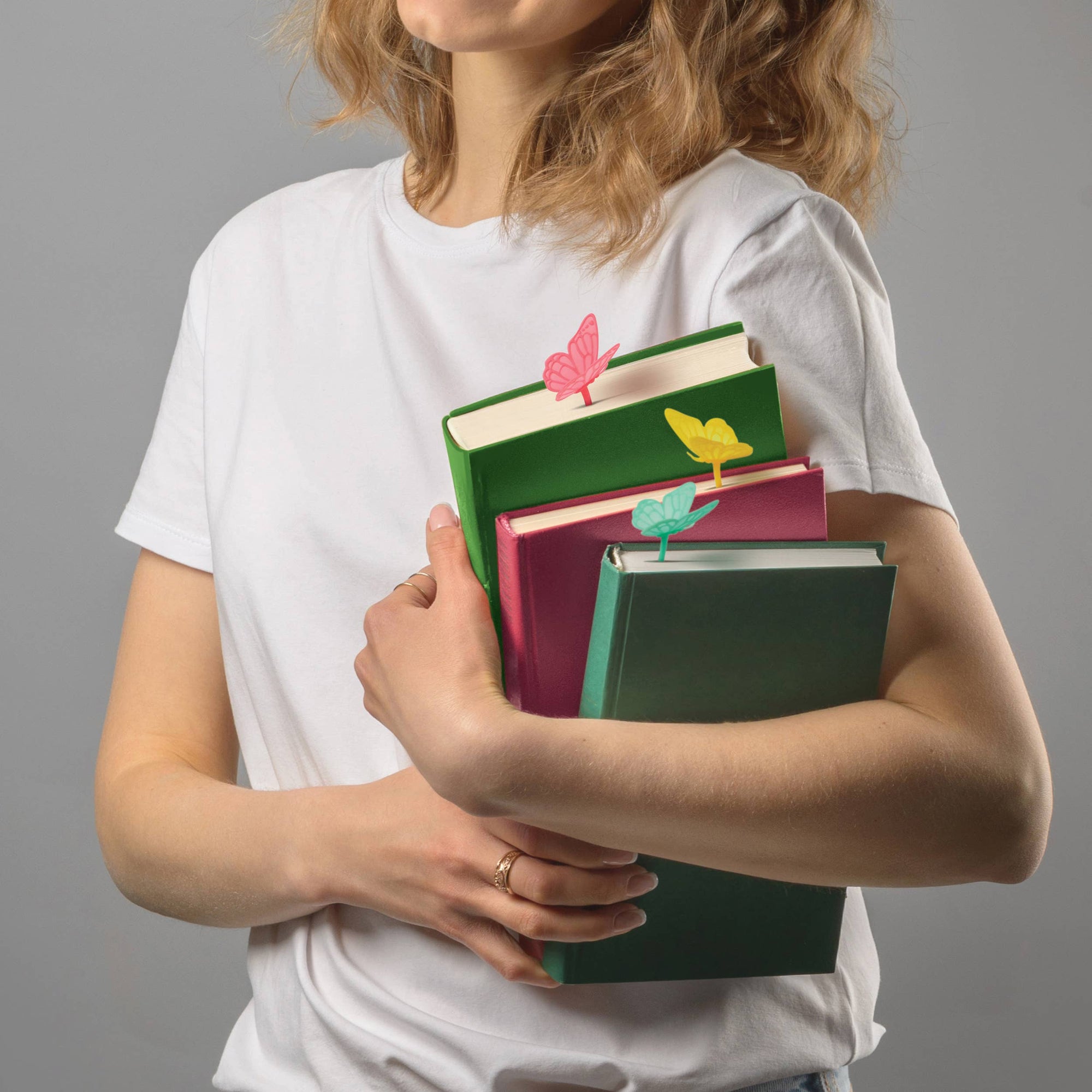 Person holding books with colorful butterfly designs on a gray background