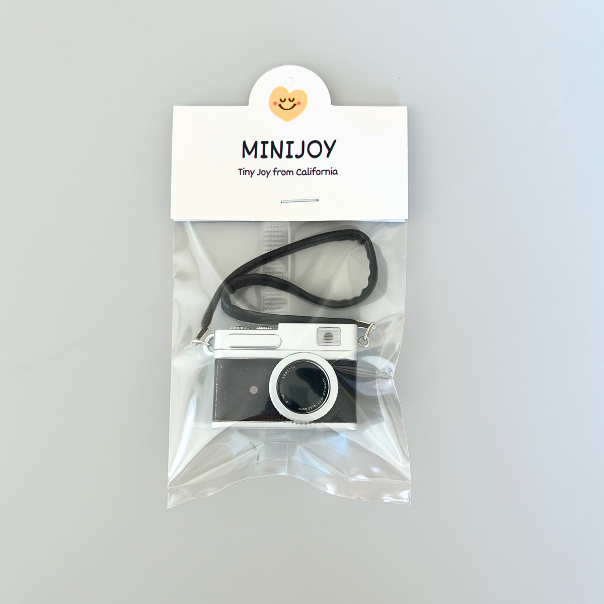 Vintage-style camera in clear packaging with 'MINIJOY' label on a gray background