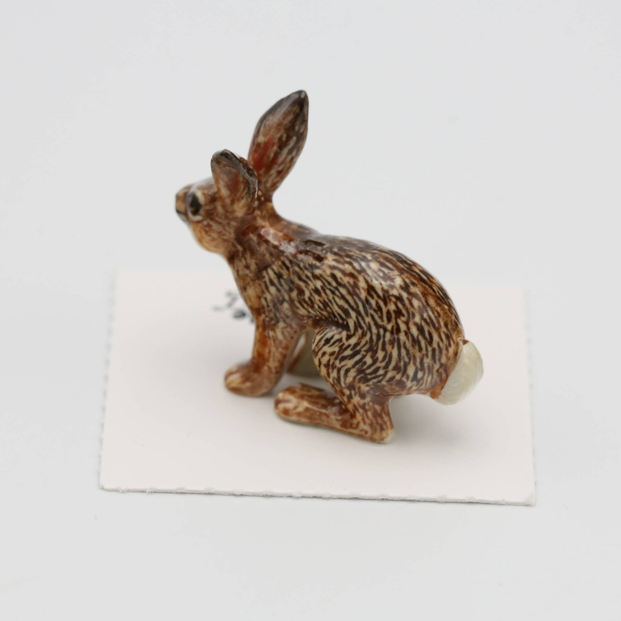 Small rabbit figurine on a white card with a light gray background