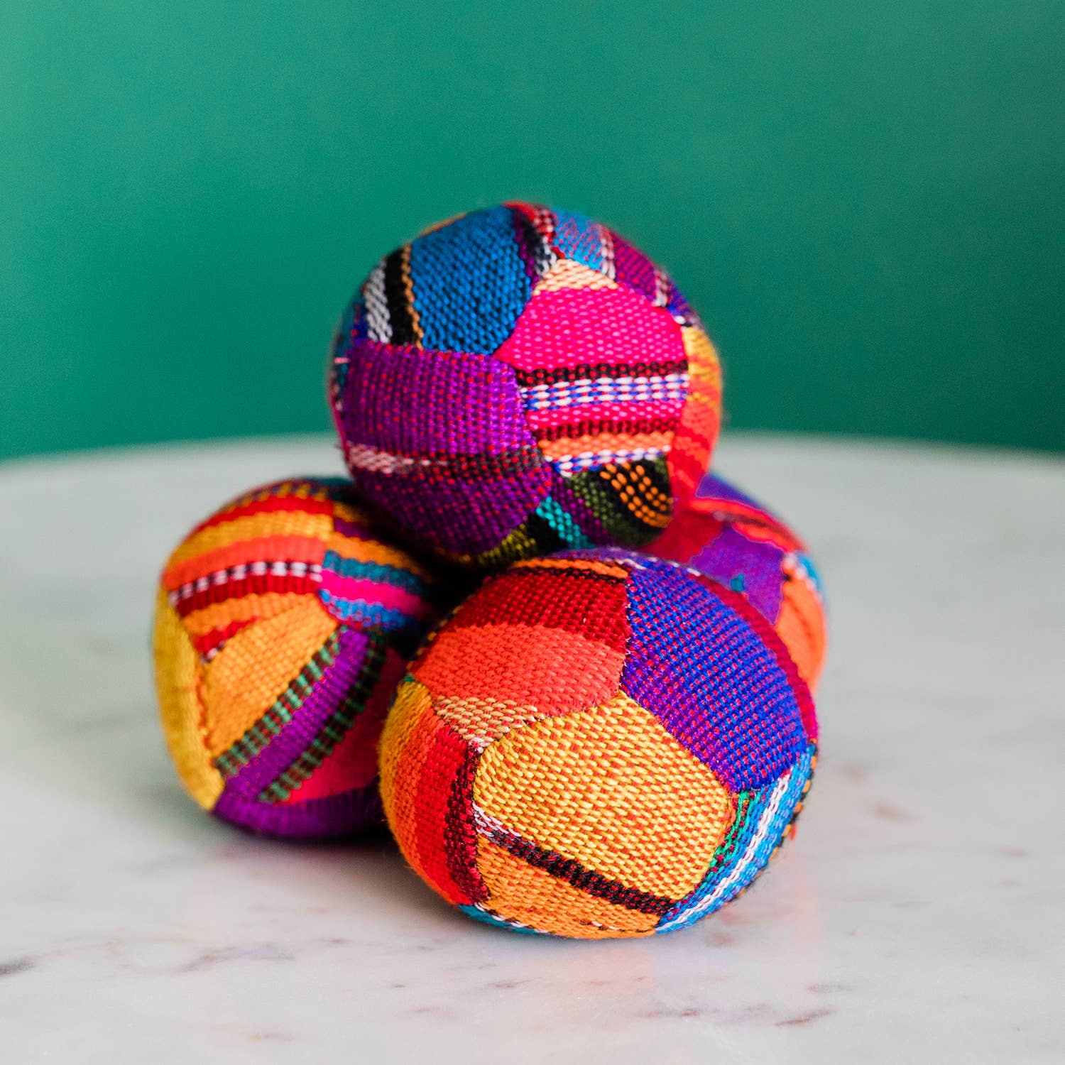 Colorful woven balls on a marble surface with a green background