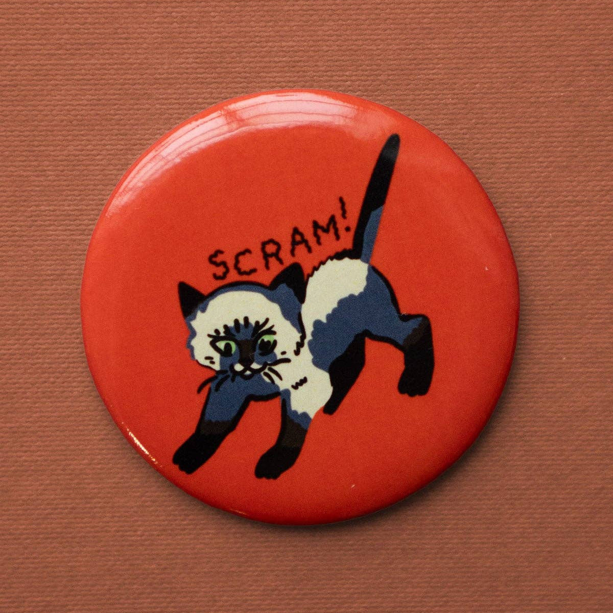 Button badge with a dog illustration and 'SCRAM!' text on a red background