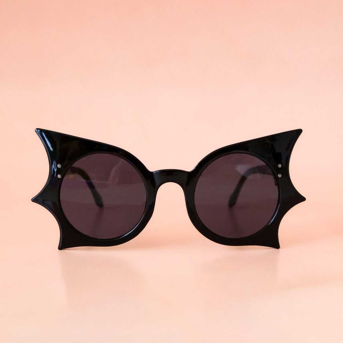 Black cat-eye sunglasses on a peach background