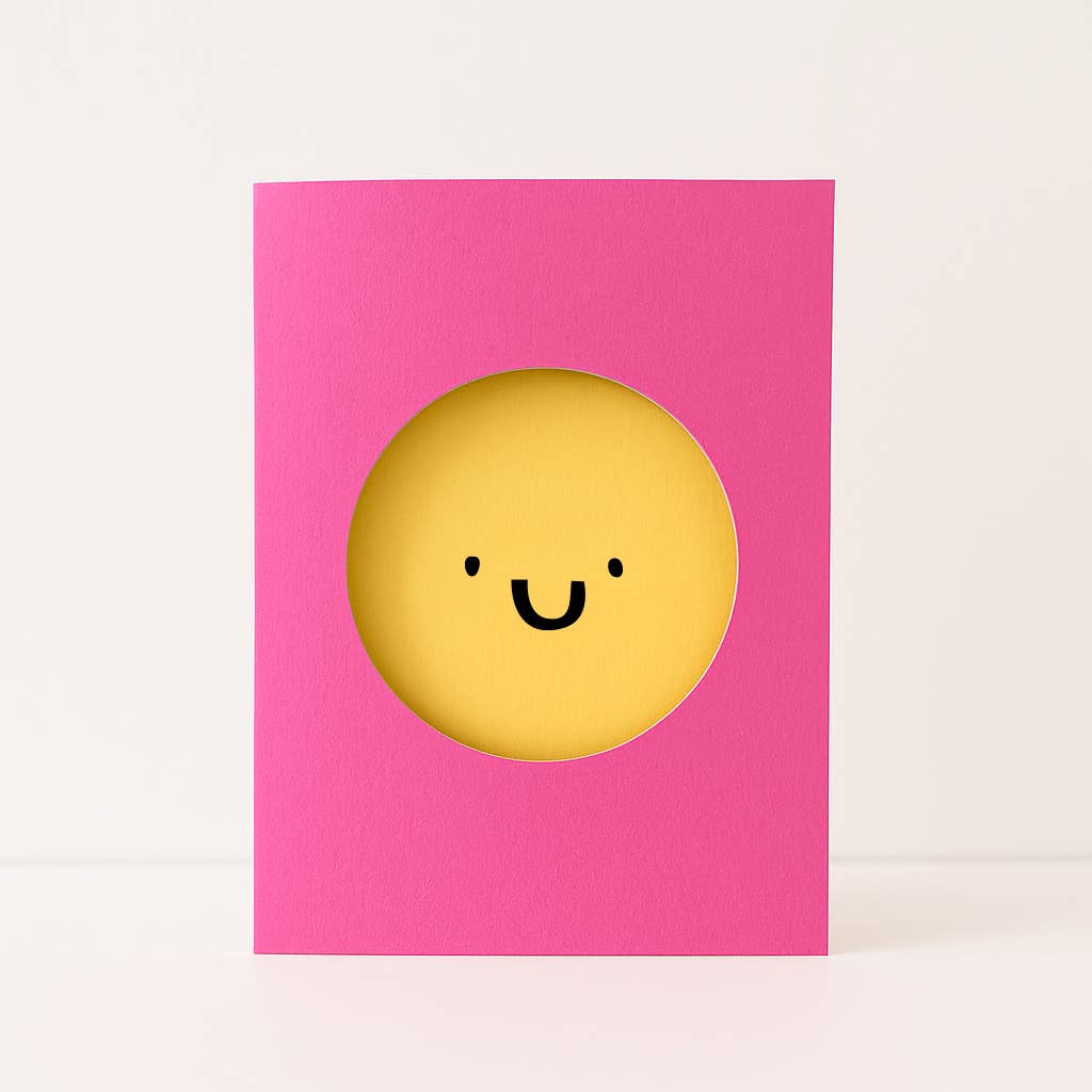 Pink card with a yellow smiley face design on a white background