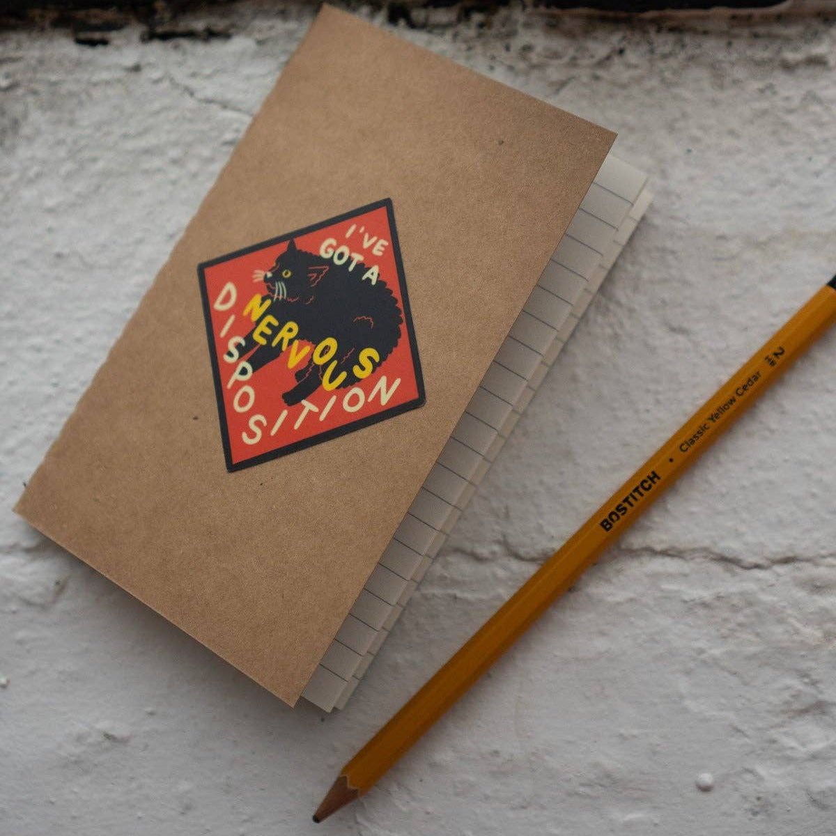 Kraft notebook with a colorful sticker and a pencil on a textured surface